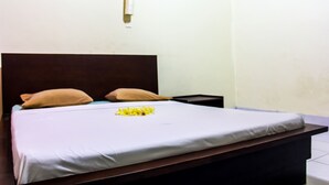 A bed with a white sheet, two pillows, and a small yellow flower arrangement. - Budhi Beach Inn (Kuta)