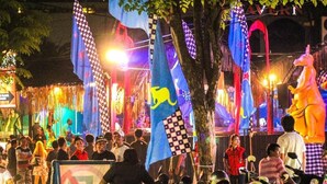 A nighttime outdoor event with people, flags, and a large statue. - Budhi Beach Inn (Kuta)
