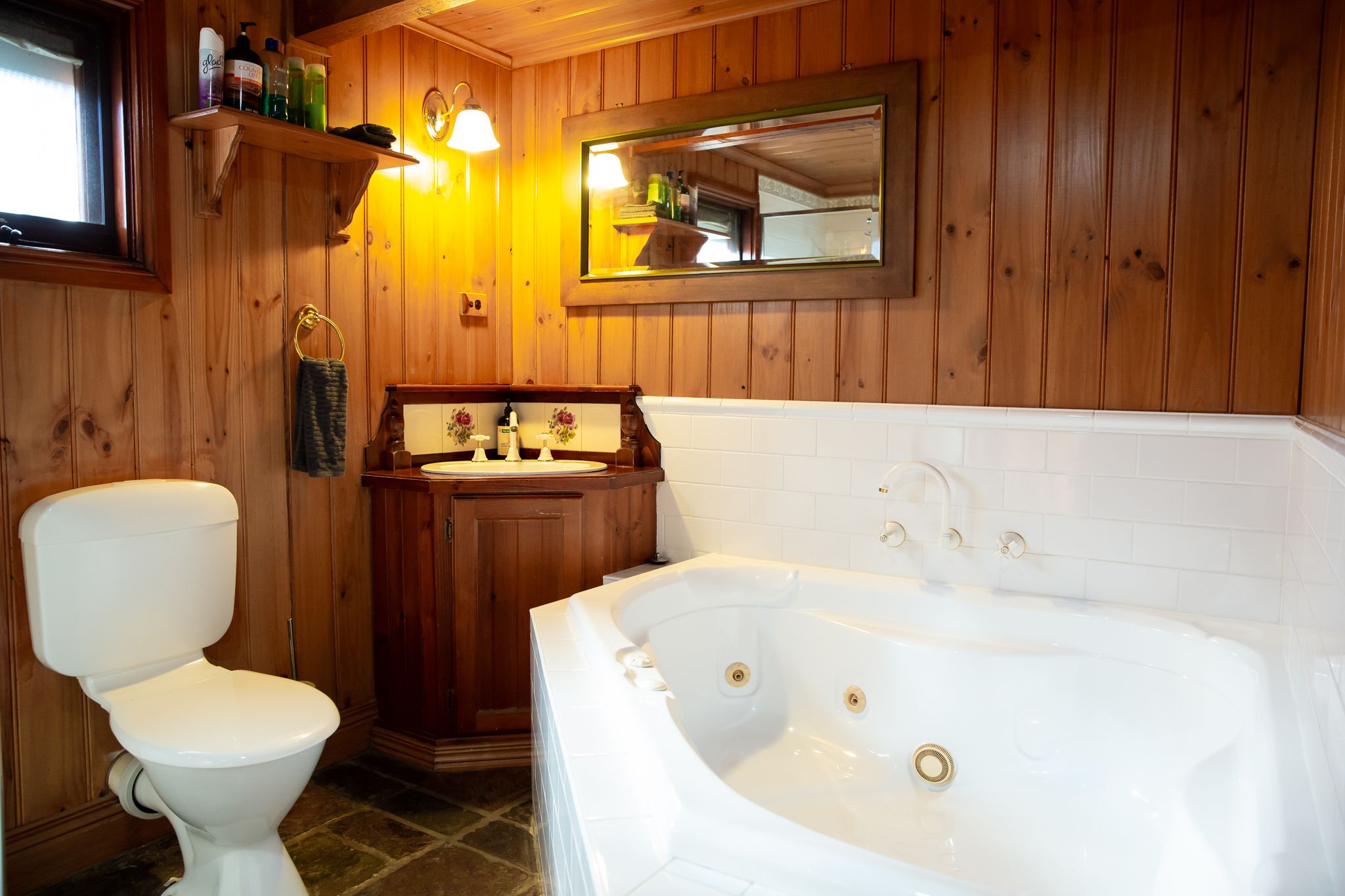 Un baño con paneles de madera, un inodoro, un lavabo y una bañera.