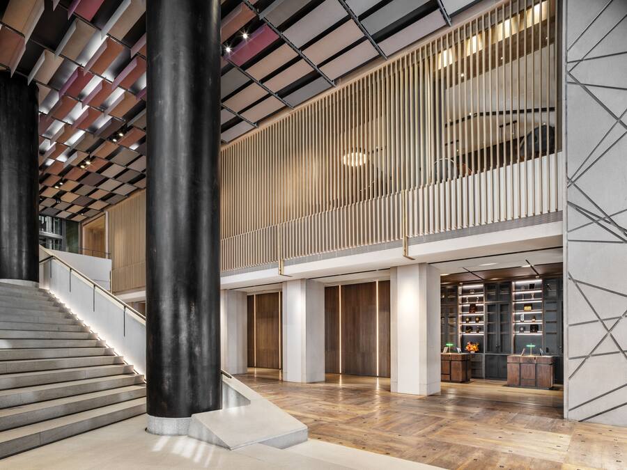 Eine großzügige Lobby mit einer Treppe, Holzboden und einem modernen Empfangstresen.