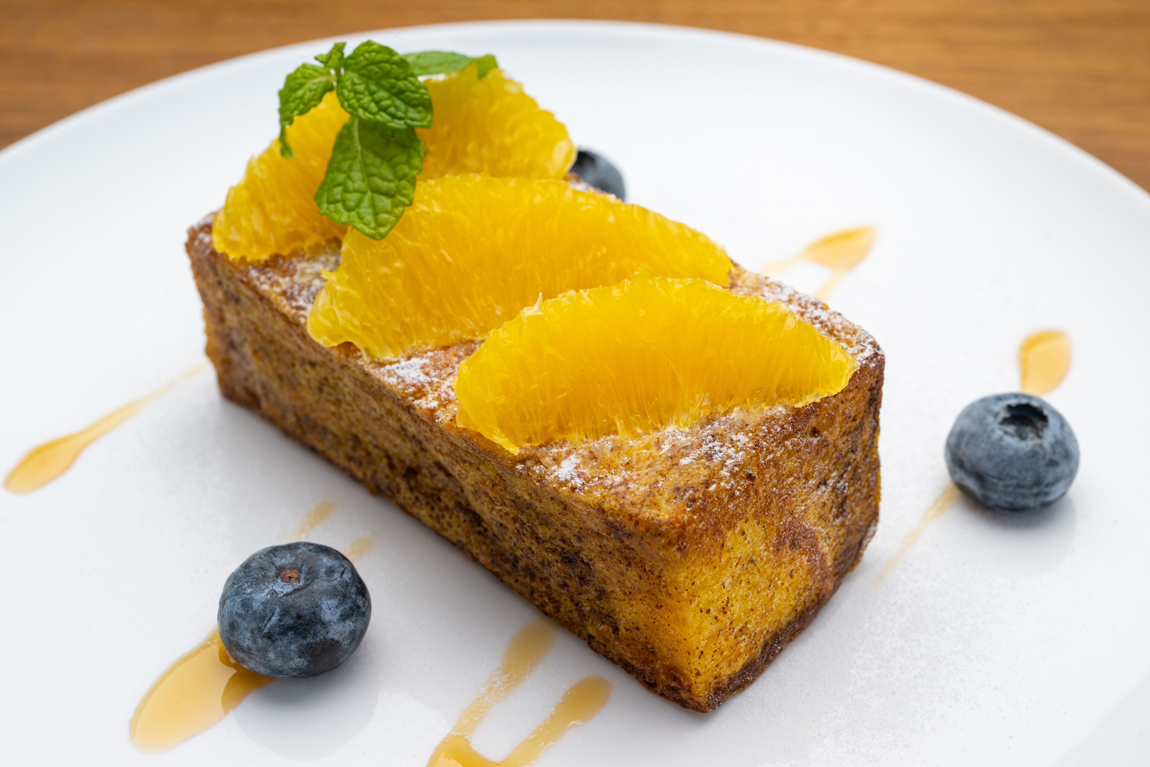 A dessert on a white plate with blueberries and orange slices.