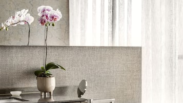 Une salle de bain moderne avec un comptoir en marbre, une orchidée en pot et un grand miroir au-dessus du lavabo.