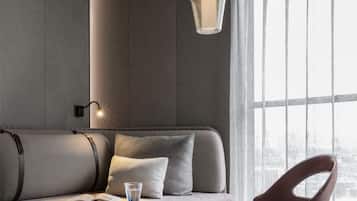 A modern living room with a sofa, a wooden coffee table, a chair, and a hanging light fixture.