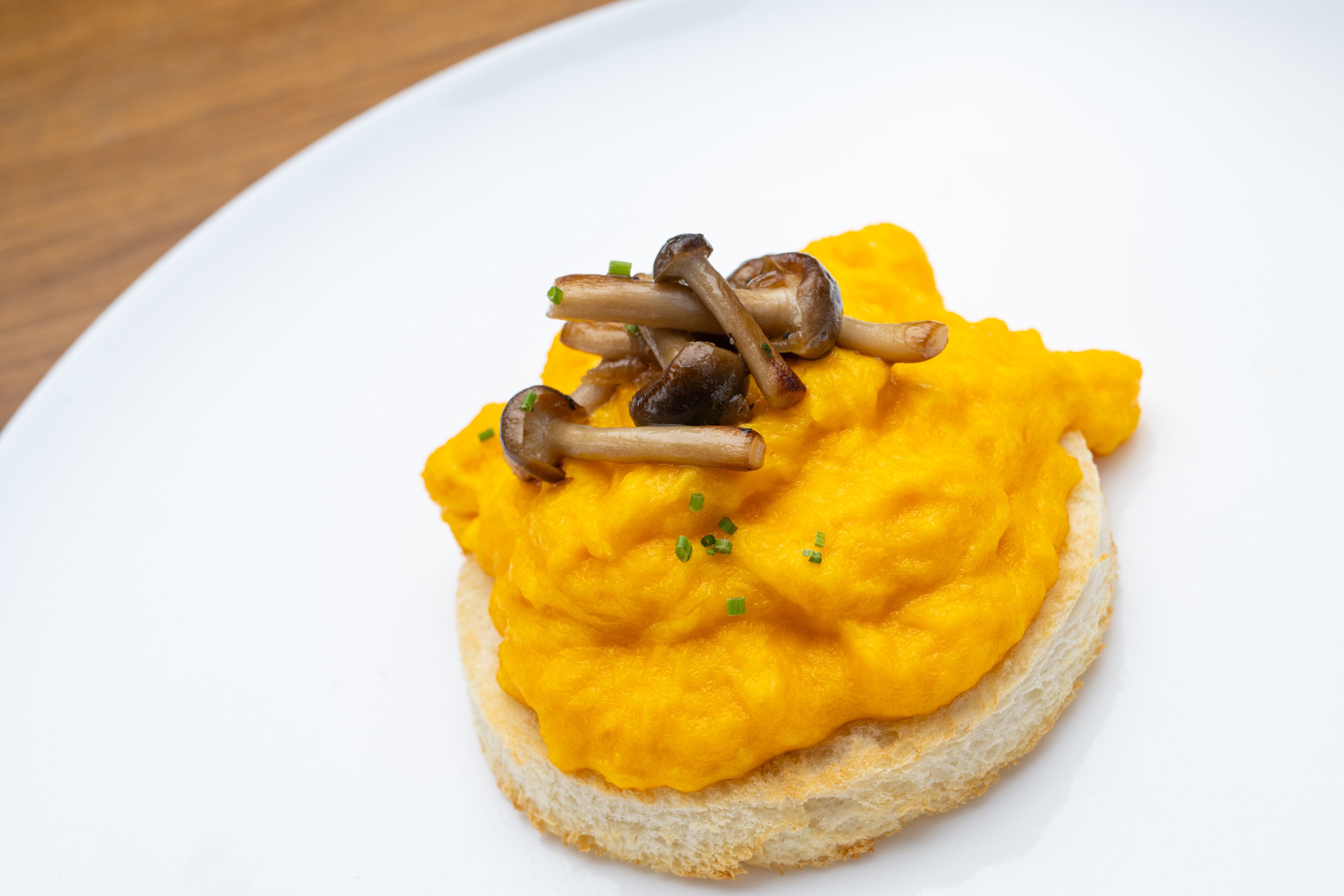 A slice of toast topped with scrambled eggs and mushrooms.