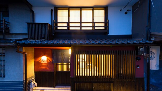 A traditional Japanese building with a wooden exterior, a tiled roof, and a sliding door.