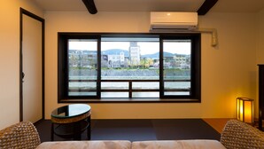 A hotel room with a large window, a bed, a small table, and a chair.