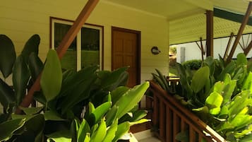 A house with a wooden front door, large windows, and a porch with wooden railings.