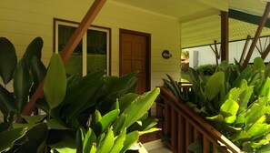 Una casa con puerta de madera, ventanas amplias y un porche con barandillas de madera.