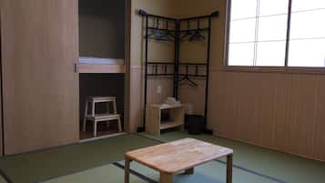 Traditional Japanese-style room with tatami flooring, featuring a wooden table, stool, and wardrobe.