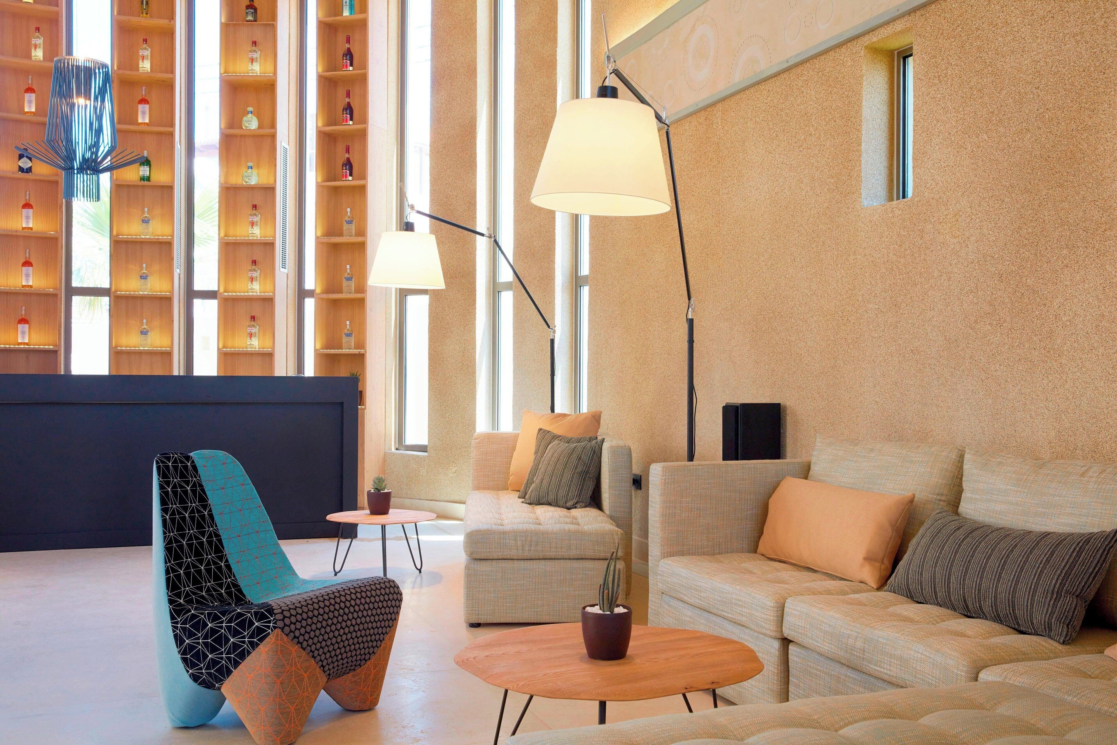 A modern interior with a sofa, armchair, and coffee table, a bookshelf, and a lamp.