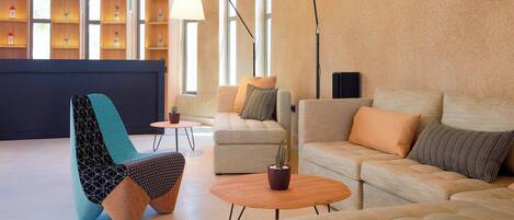 Un interior moderno con un sofá, un sillón y una mesa de centro, una estantería y una lámpara.