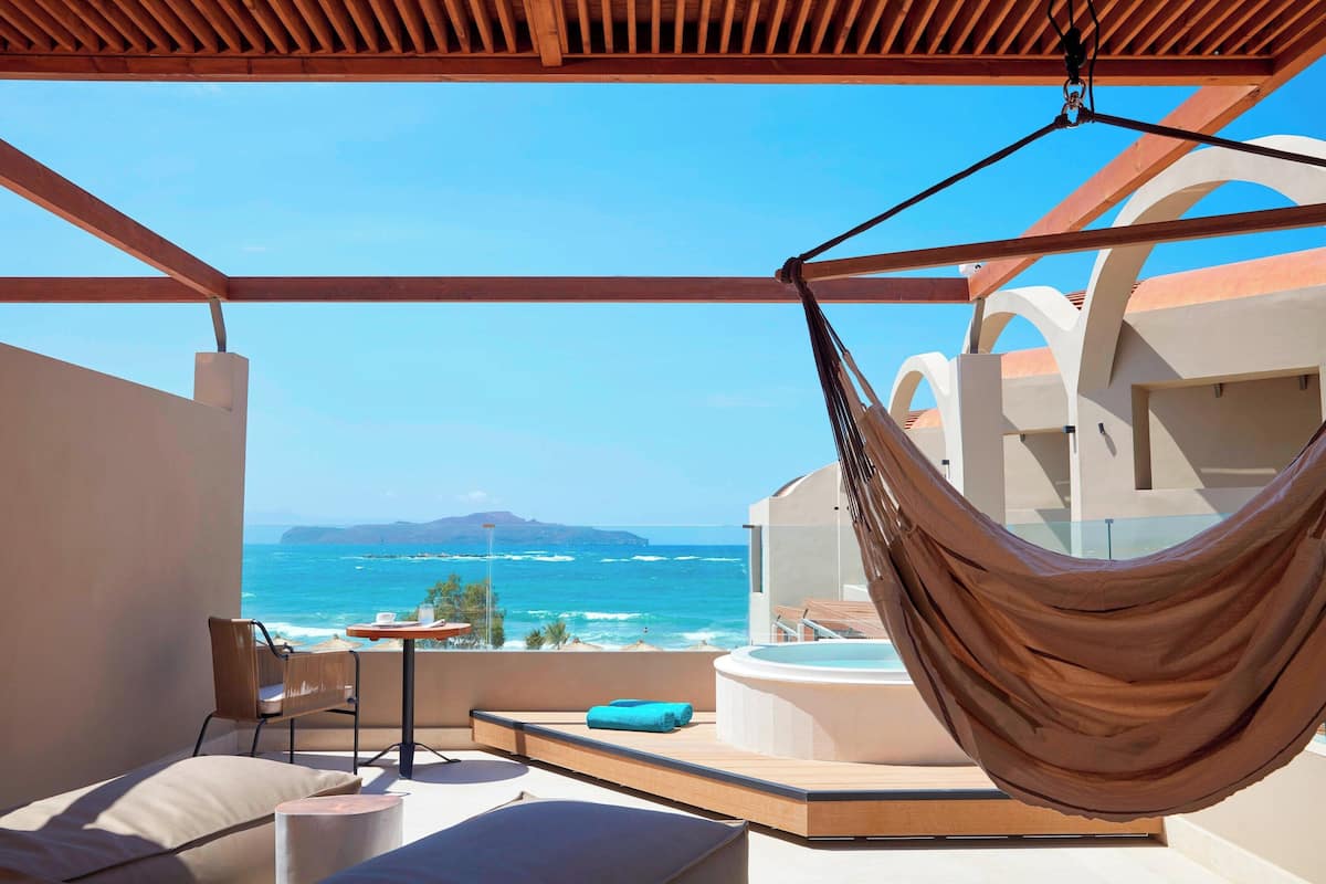 Ein Balkon mit einer Hängematte, einem Whirlpool und Blick aufs Meer.