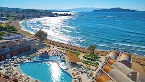 Un resort con una piscina grande, acceso a la playa y vistas al mar.