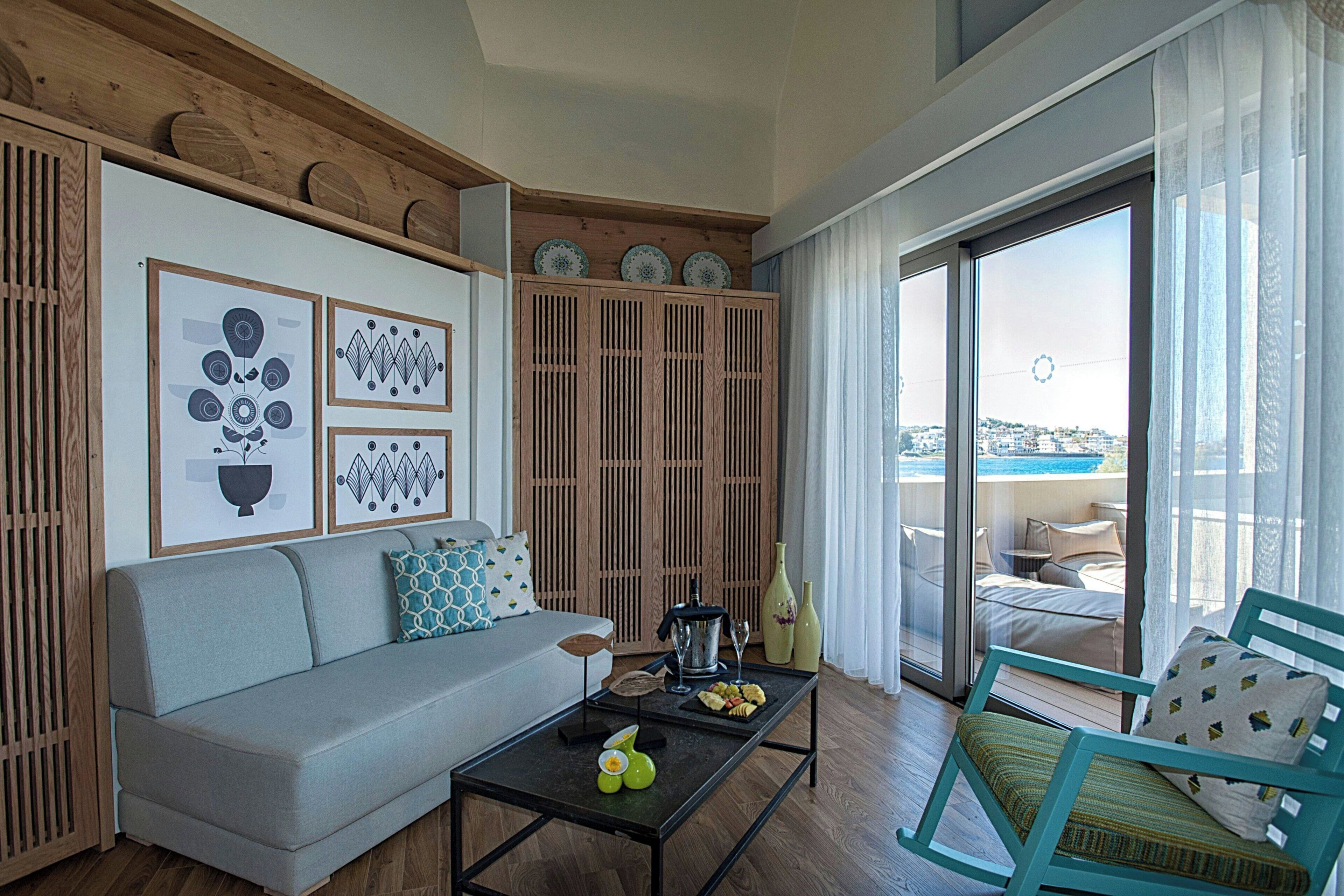 Un salon comprenant un canapé, une table basse et donnant sur un balcon aménagé avec des sièges d’extérieur.