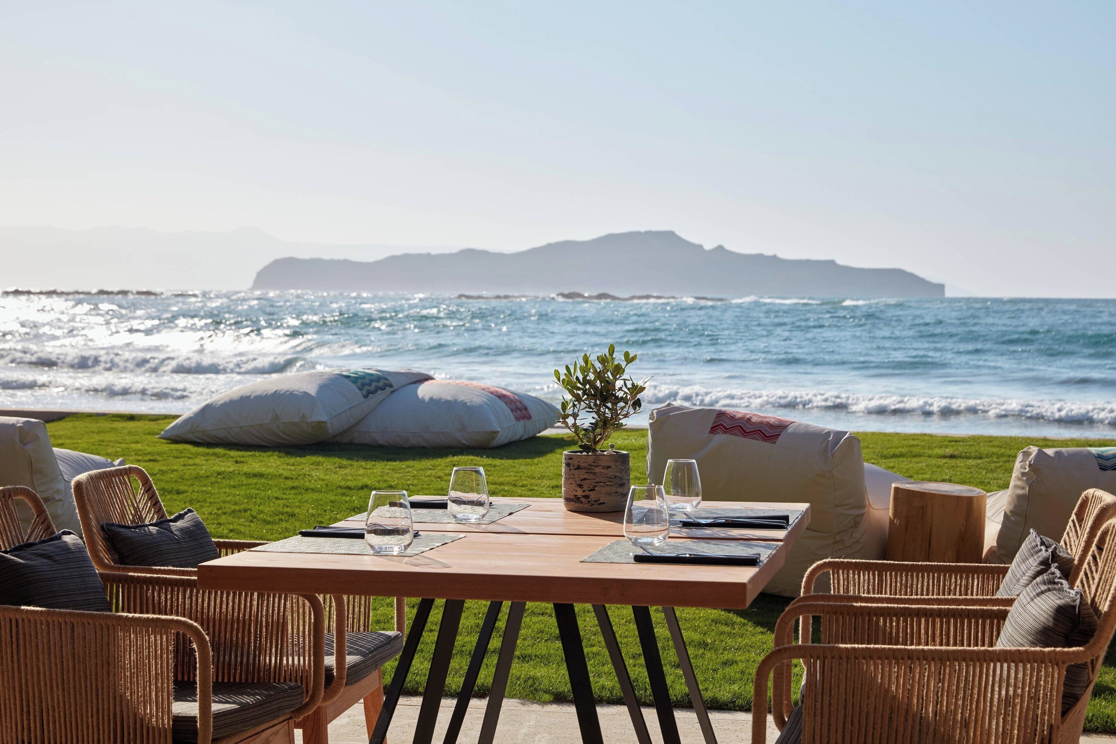 Un comedor al aire libre con mobiliario de mimbre y vista al océano.