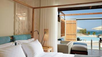 A hotel room with a bed, a bedside table, a lamp, and a view of a pool and ocean.