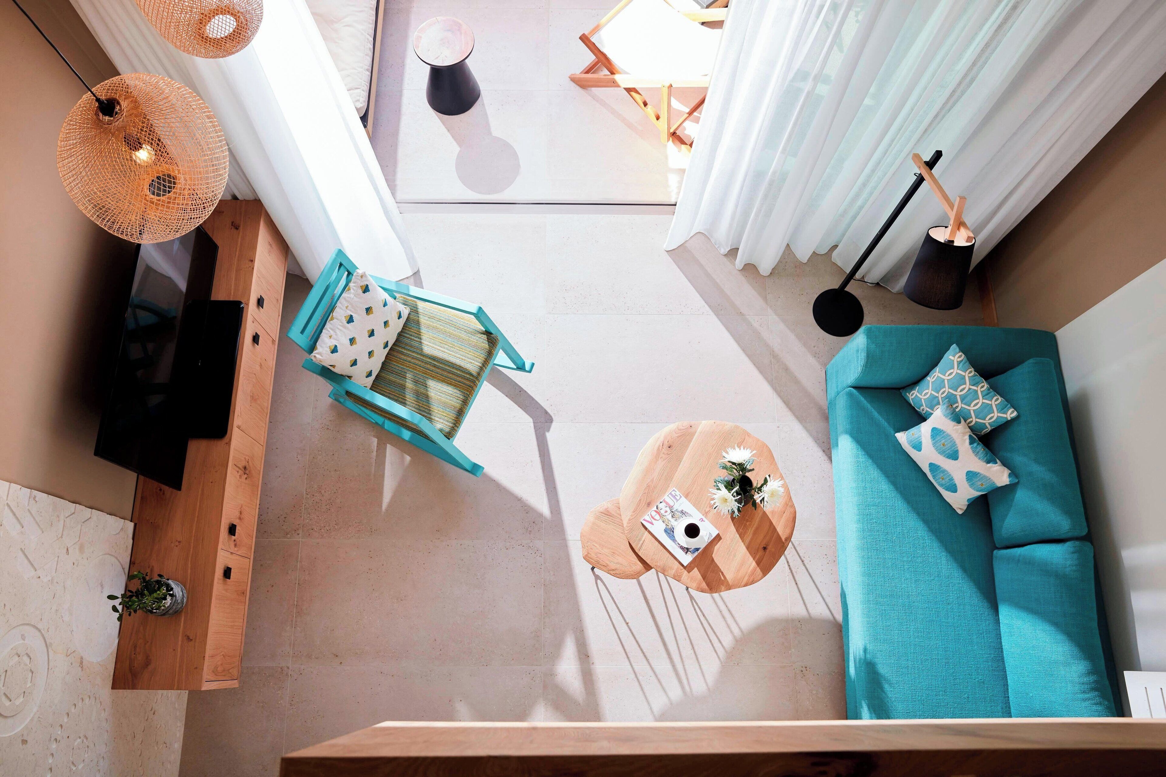 A modern living room with a teal sofa, wooden coffee table, and a blue chair.