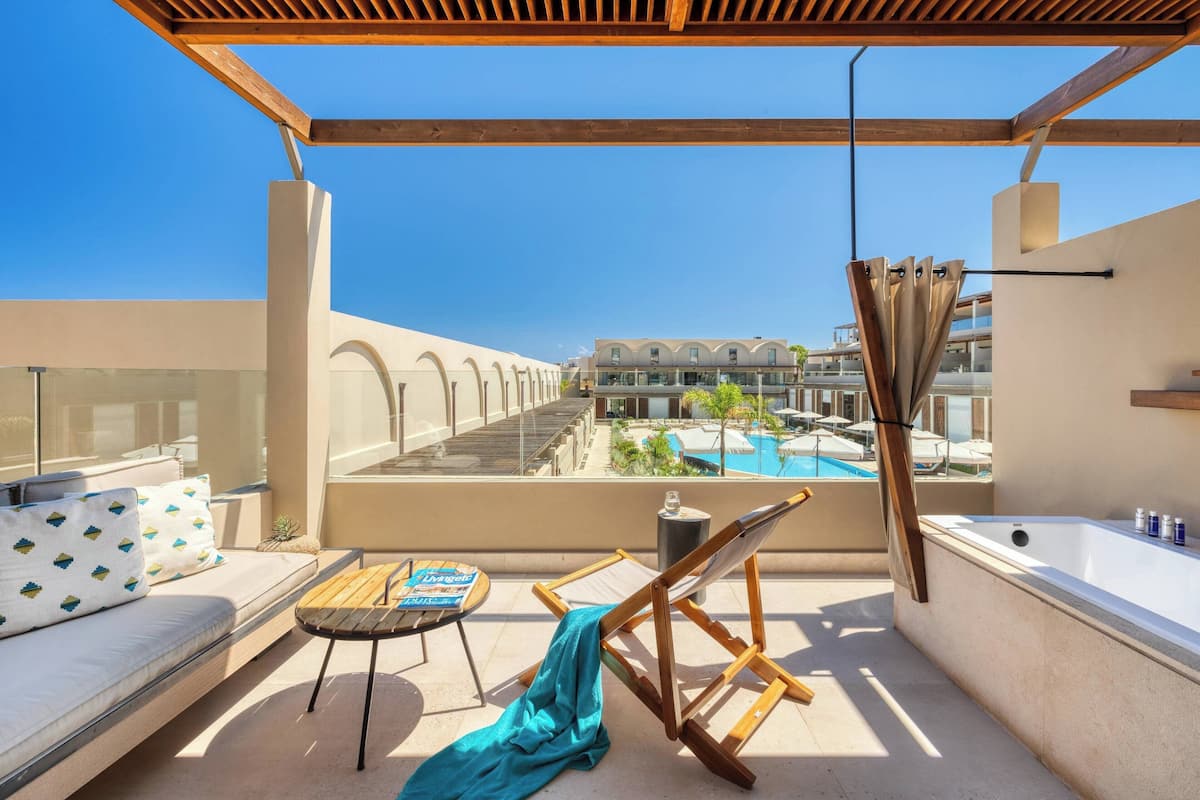 Ein Balkon mit einer Couch, einem kleinen Tisch, einem Stuhl, einem Handtuch und einer Badewanne.