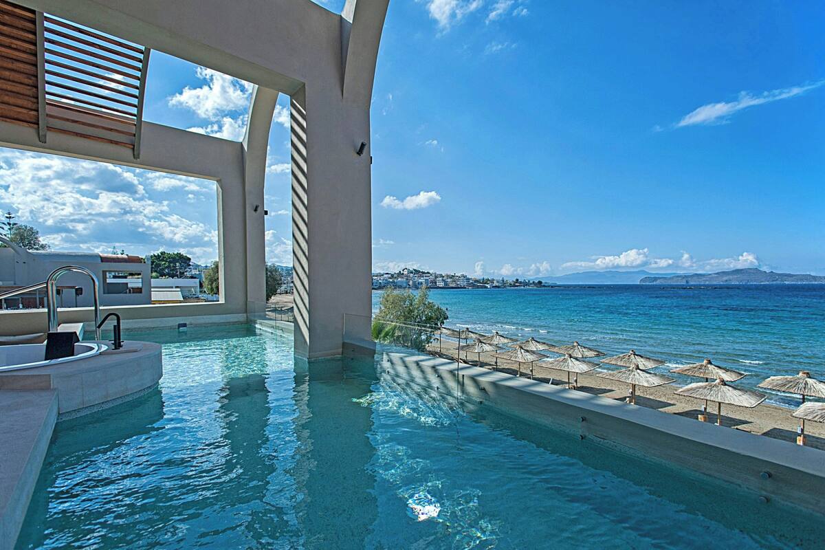 Ein Poolbereich mit Blick auf das Meer und ferne Berge.