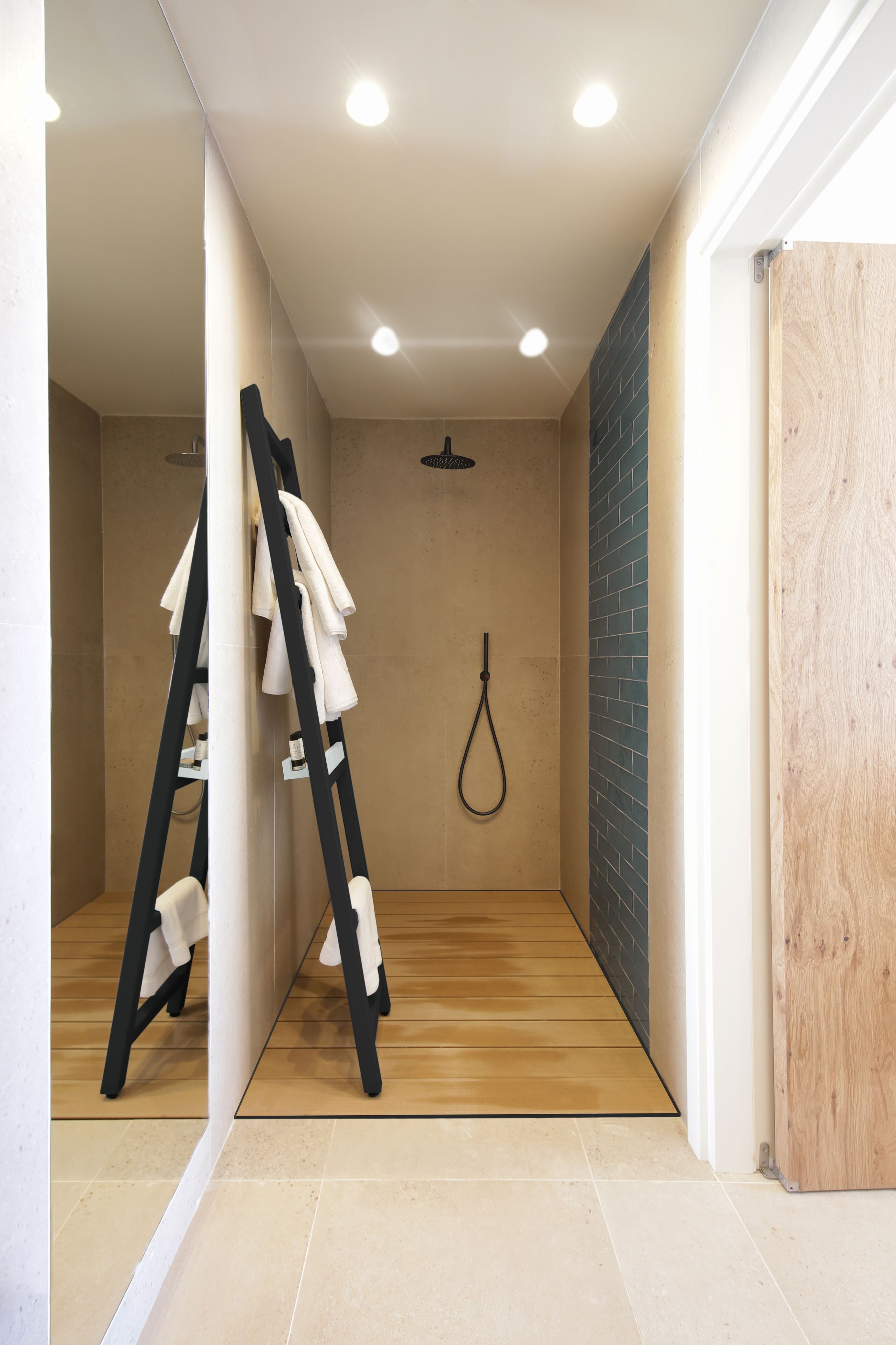 A modern bathroom with a shower, a towel rack, and a wooden floor.