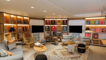 A modern living room with a sofa, chairs, a coffee table, and a bookshelf with various items.