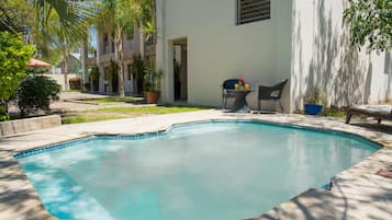 Una piscina al aire libre, sillones reclinables de piscina