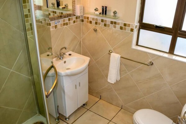 A bathroom with a sink, mirror, and towel rack. - Peo Luxury Apartments (Maun)