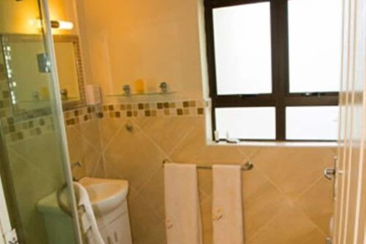 A bathroom with a shower, toilet, and sink. There are two towels hanging on a rack.