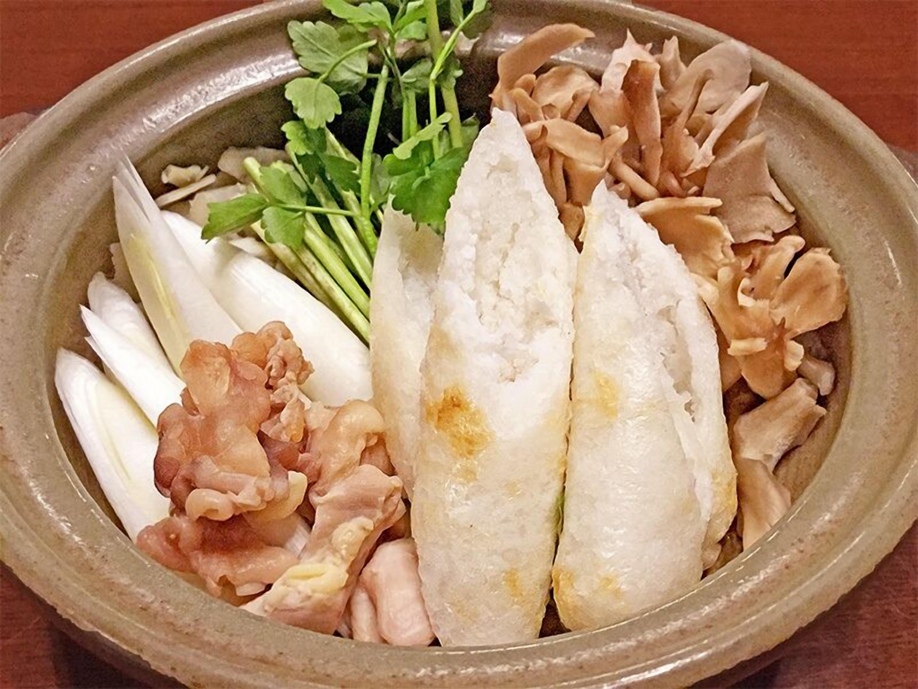 A ceramic dish with various food items including fish, mushrooms, and leafy greens.