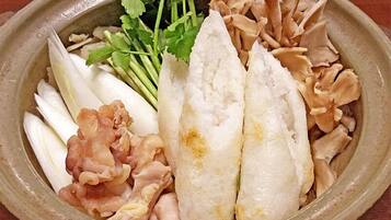 A ceramic dish with various food items including fish, mushrooms, and leafy greens.