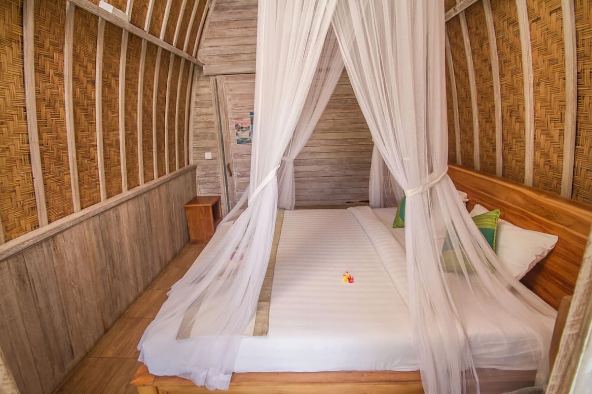 Een kamer met een bed, houten wanden en een geweven plafond.