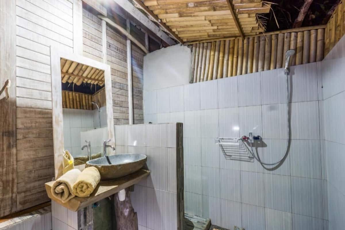 Een badkamer met een houten plafond, een wastafel met kom, een spiegel en een douchegedeelte.