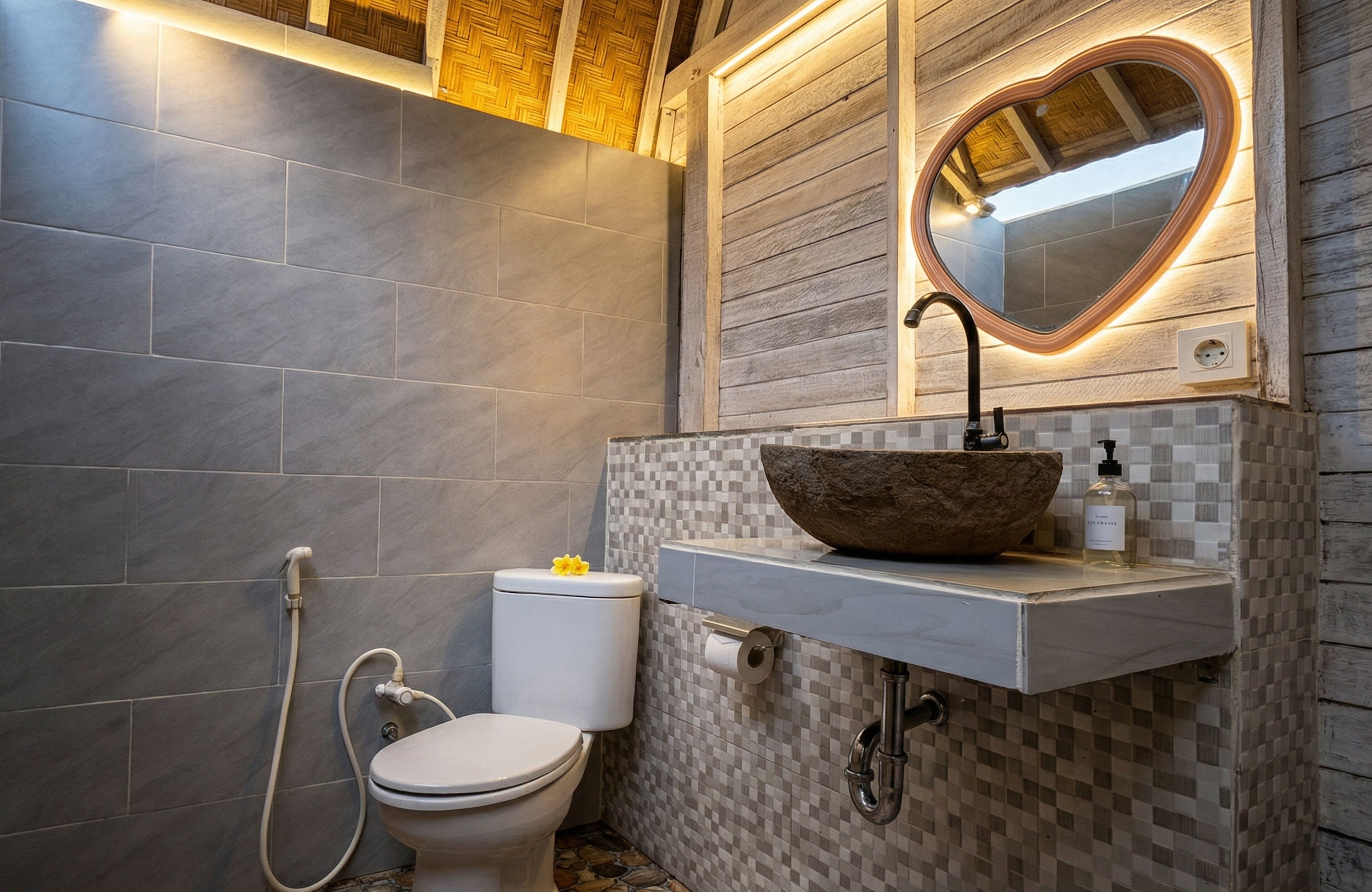 A bathroom with a white toilet, a heart-shaped mirror, and a vessel sink.