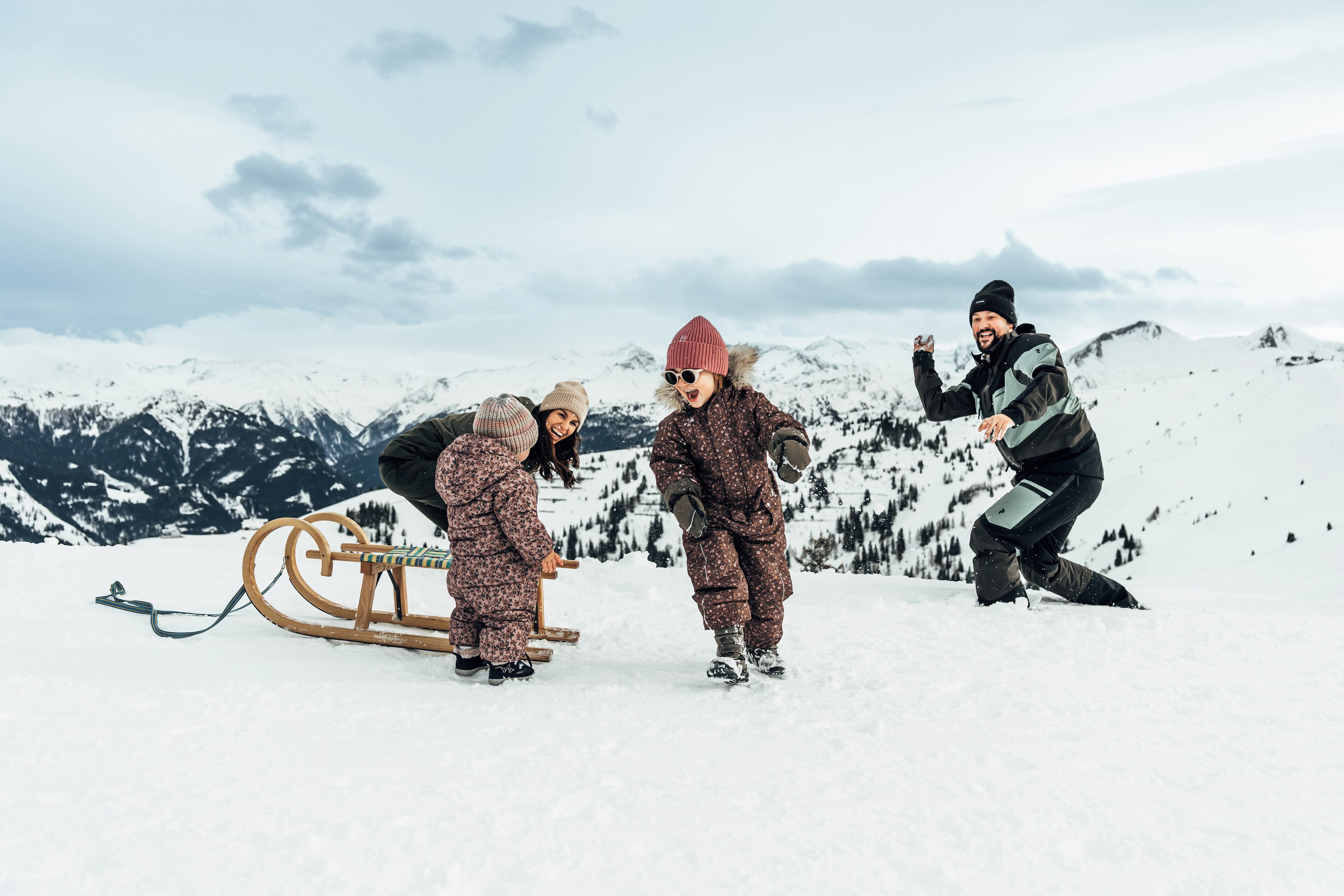 Three people on a snowy mountain with a sled.