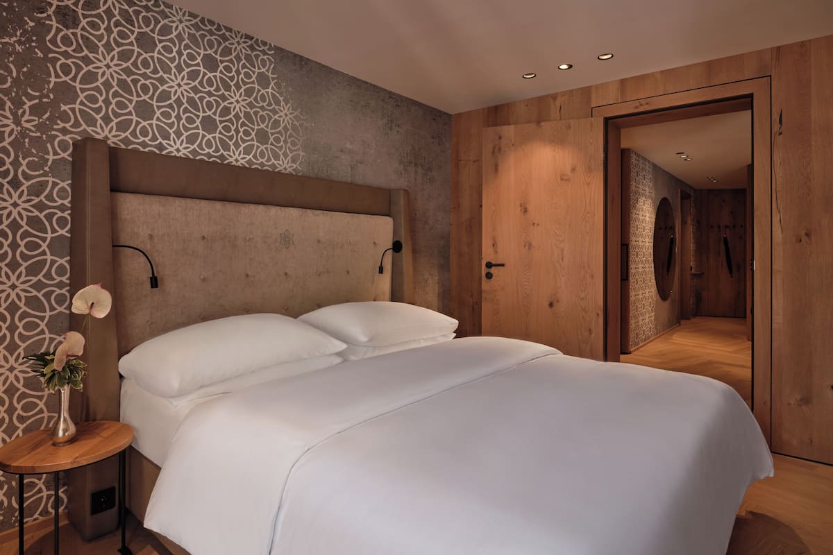 Ein modernes Schlafzimmer mit einem großen Bett, einem Nachttisch mit einer Vase und einer Wand mit Muster.