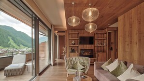 Amplia sala de estar con un ventanal que ofrece vistas a un paisaje montañoso, chimenea y paneles de madera.