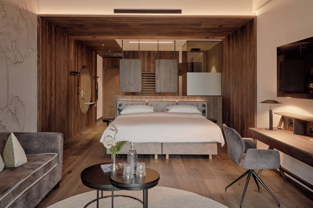 Ein modernes Schlafzimmer mit einem großen Bett, einer Couch, einem Couchtisch und einem Fernseher.