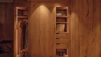 A wooden wardrobe with multiple compartments, including hanging space, drawers, and shelves.