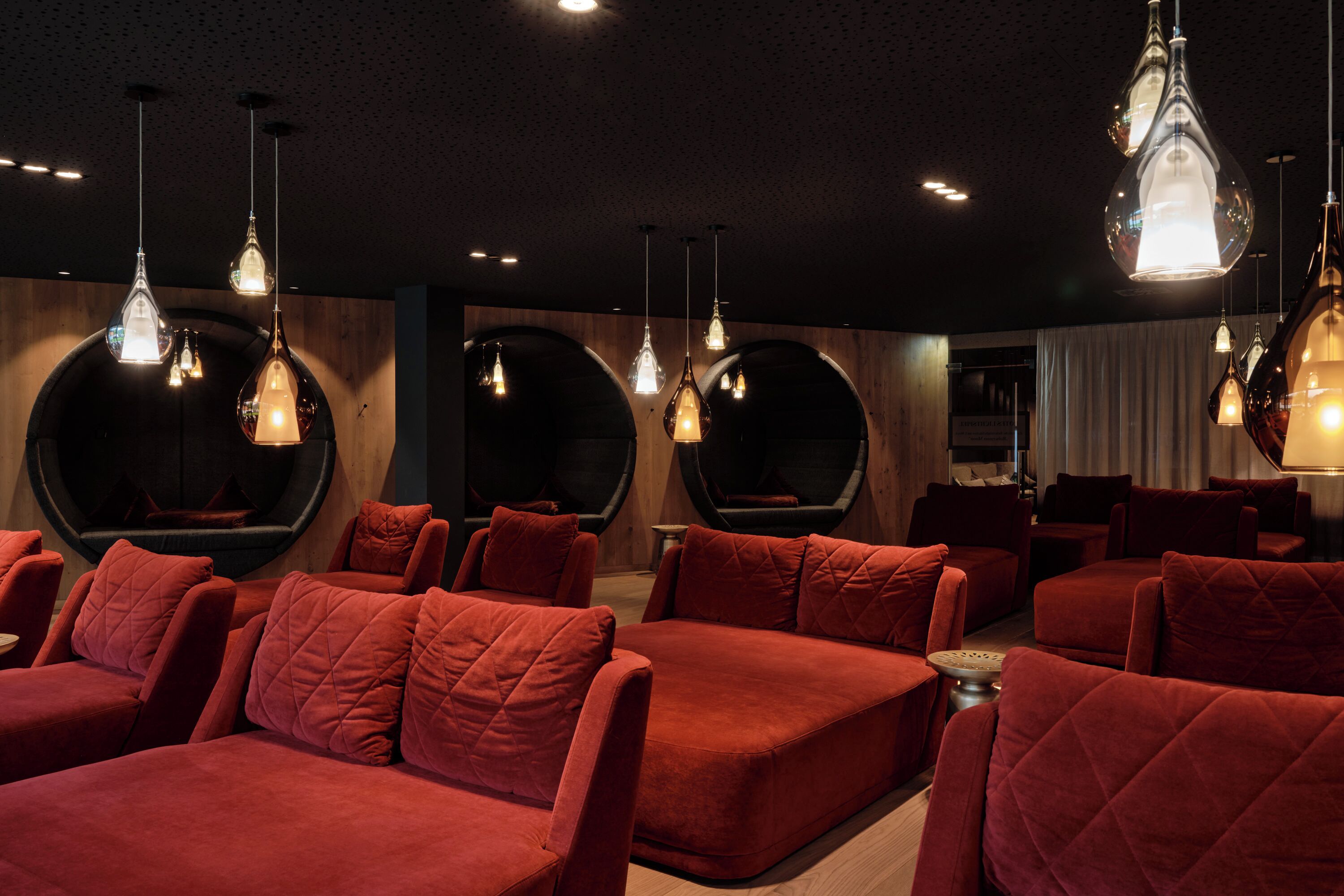 Un interior moderno con asientos tapizados en rojo, sillas esféricas originales e iluminación colgante.