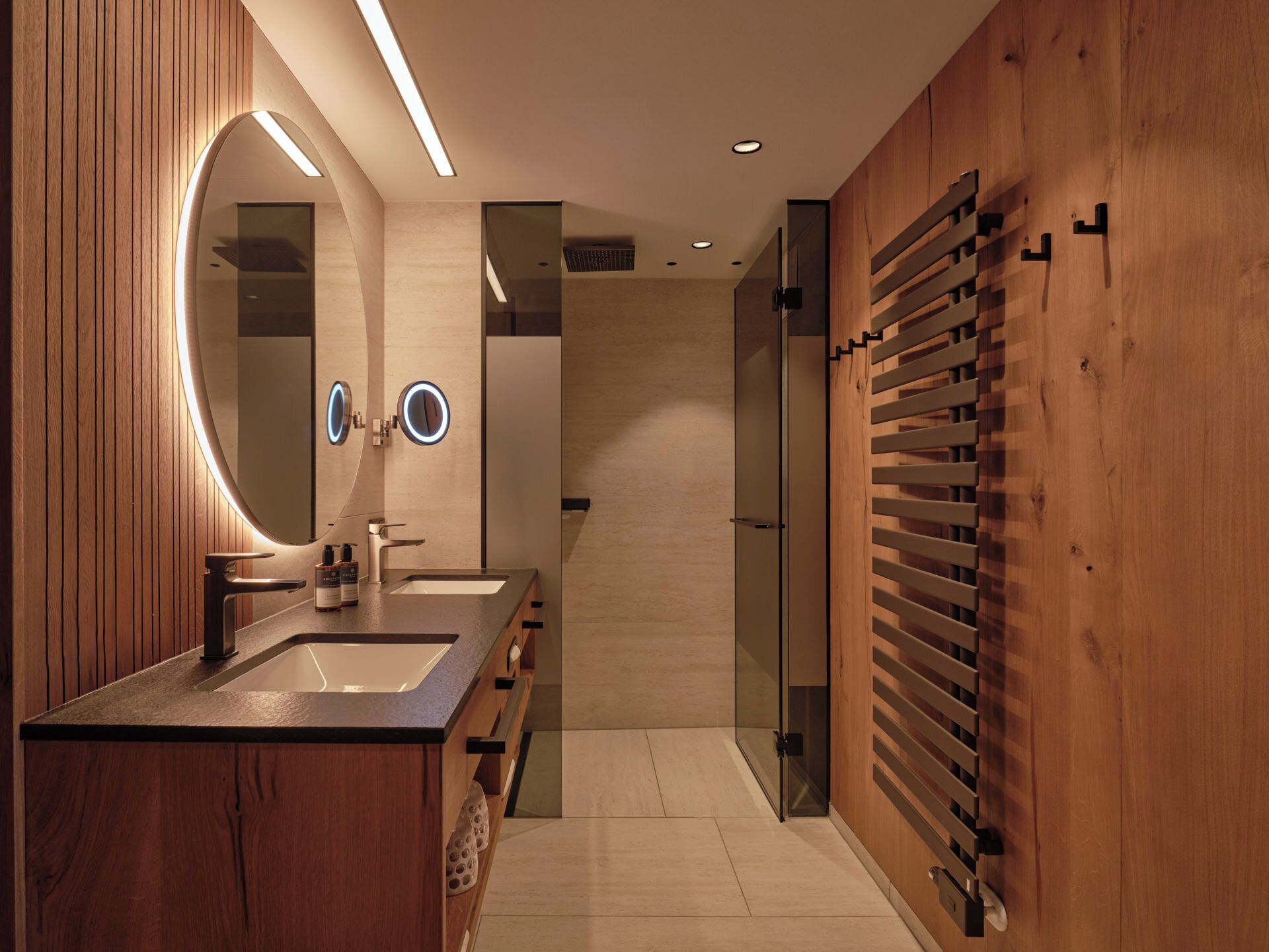 A modern bathroom with wooden paneling, a double sink vanity, and a towel rack.