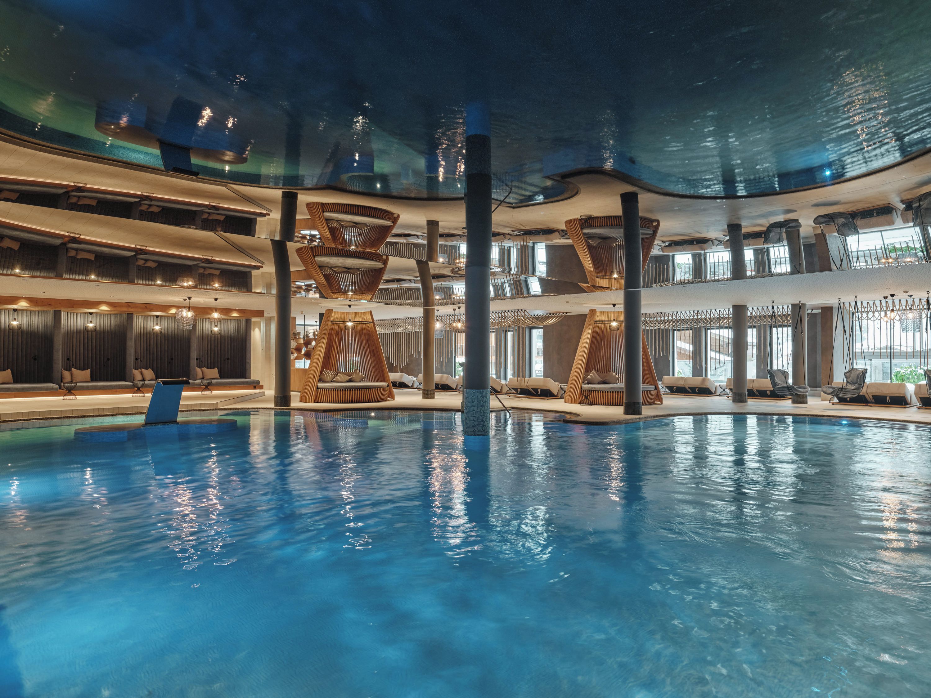 Une piscine intérieure dotée de gradins et de fauteuils suspendus.