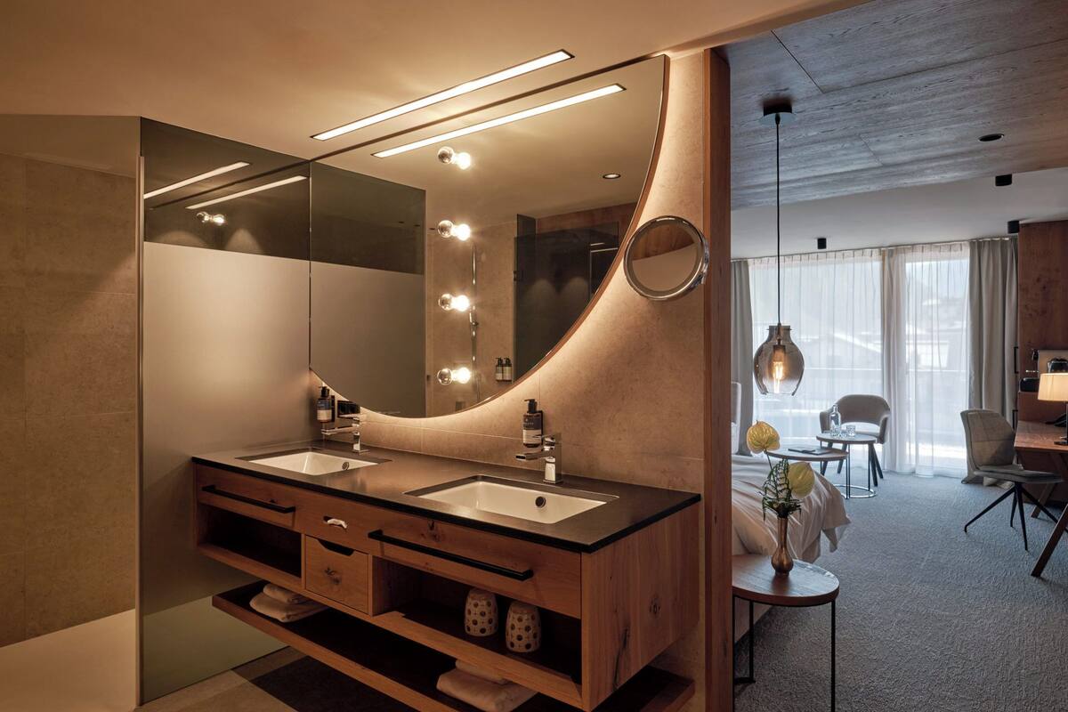 Ein modernes Badezimmer mit zwei Waschbecken, einem großen Spiegel und einem Waschtisch mit Schubladen.