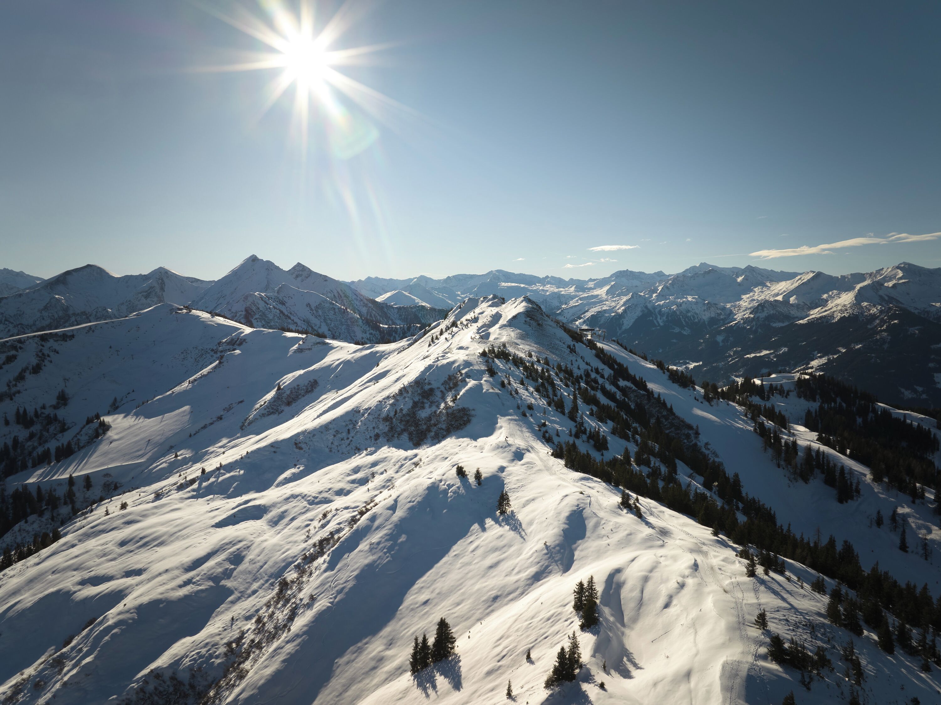 Un paysage montagneux enneigé, avec un ciel dégagé et des montagnes à l’horizon.