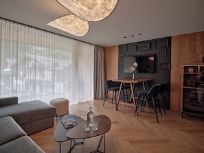 A modern living room with a sofa, a coffee table, and a dining area with chairs and a small table.