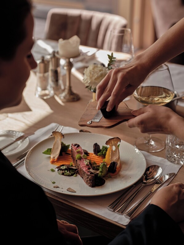 A dining table with a plate of food, cutlery, and a wine glass.