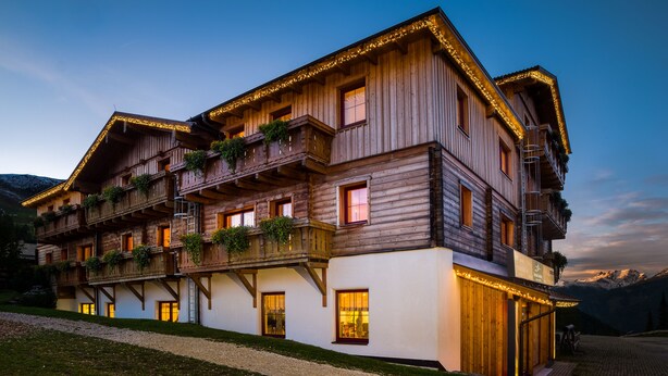 Un chalet en bois doté de balcons, de grandes fenêtres et d’un chemin de gravier menant à l’entrée.