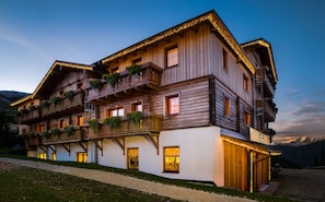 A wooden chalet with balconies, large windows, and a gravel path leading to the entrance.