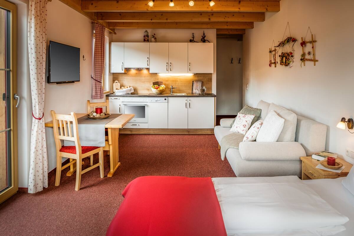 Una habitación acogedora con cama, una mesa de comedor con sillas, una zona de cocina y un sofá.