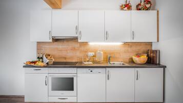 A modern kitchen with white cabinets, a wooden countertop, and a built-in oven.