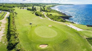 Un campo de golf con vista al mar, un búnker arenoso y un fairway bien cuidado.